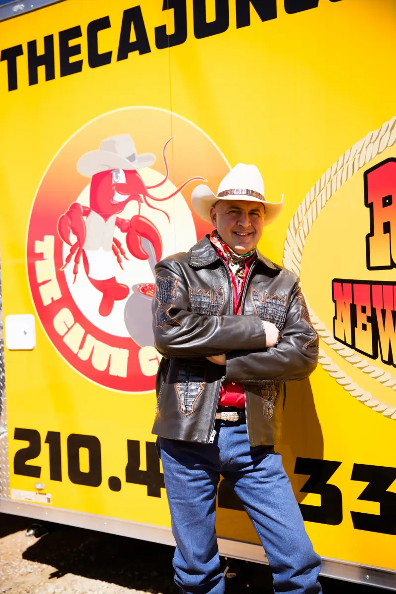 Michael Palermo in leather jacket, cowboy hat, arms crossed and leaning against the food truck